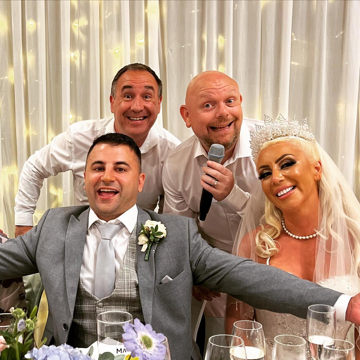 The Sing Along Waiters surprising newlyweds at luxury UK wedding reception, award-winning singing duo performing with bride and groom, featuring elegant backdrop with fairy lights, 30 years of premium entertainment experience in Manchester and North West