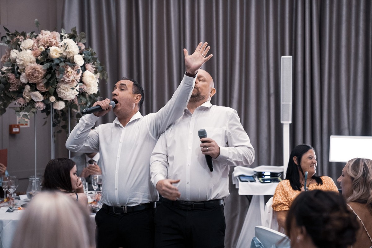 Singing waiters entertaining wedding guests with a lively performance at a reception.