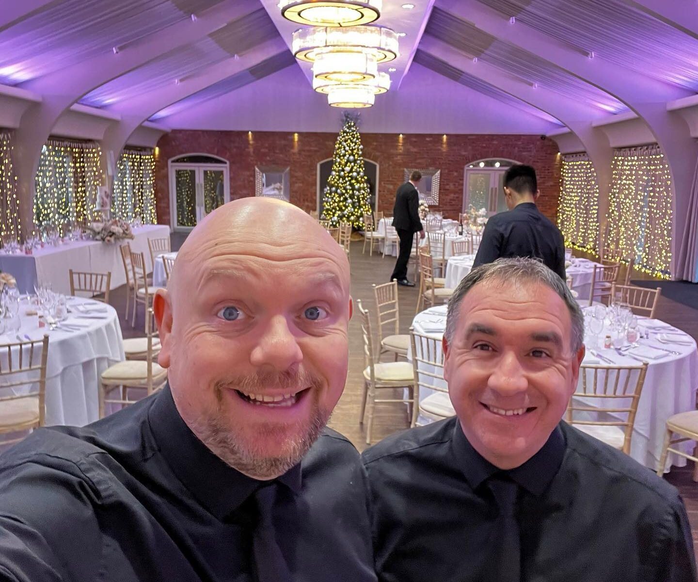 The Sing Along Waiters® posing in the beautifully decorated Peel Suite at Colshaw Hall, featuring elegant table settings and twinkling fairy lights, ready for a memorable wedding performance.